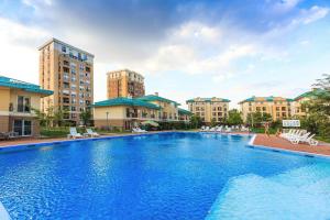 Ein großer blauer Swimmingpool mit Gebäuden im Hintergrund in der Unterkunft Ama Studio Cosmopolis in Tunari