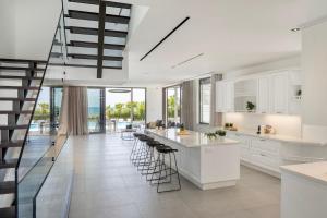 a kitchen with white cabinets and bar stools at Villa JoJo Seafront in Ayia Napa