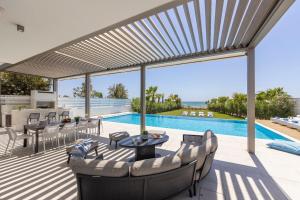 a patio with a table and chairs and a pool at Villa JoJo Seafront in Ayia Napa