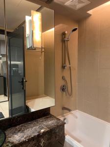 a bathroom with a shower and a tub with a mirror at Sunway Resort Suite & Theme Park in Petaling Jaya