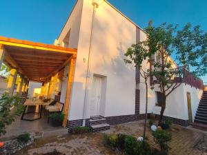a white building with a table and a tree at Kaffeinn Specialty Coffee Baile 1 Mai in Baile Unu Mai