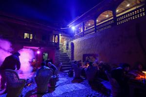 un gruppo di persone sedute in una stanza di notte di Basho Mud Huts a Bashist