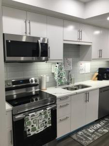 a kitchen with a stove and a microwave at Almost Heaven - Cozy 2BDRM APT near Heritage Park,Spruce Meadows & Banff-SW Calgary in Calgary