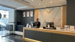 a man sitting at a counter in a lobby at Uptown Hotel Apartments Abu Dhabi by Gewan in Abu Dhabi