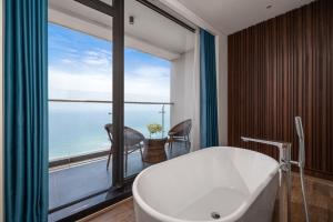 岘港Canvas Danang Beach Hotel的带浴缸和大窗户的浴室