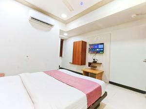 a bedroom with a white bed and a tv at Hotel Anushri Villa in Ahmedabad +22 photos