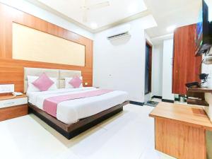 a bedroom with a bed and a desk and a television at Hotel Anushri Villa in Ahmedabad