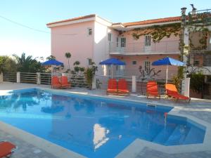 a swimming pool with chairs and umbrellas in front of a house at Odyseas Studios in Lourdata