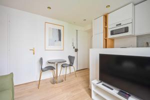 un salon avec une télévision, une table et des chaises dans l'établissement Cosy Nest - 2P - The 16th arrondissement, à Paris 7 autres photos