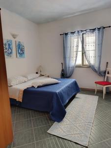 a bedroom with a blue bed and a window at Casa Caterina in Tertenìa