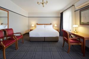 a bedroom with a bed and two chairs and a desk at Brassey Hotel - Managed by Doma Hotels in Canberra