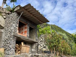a stone building with a window on a mountain at Vistalinda Farmhouse in Fajã dos Vimes +31 photos