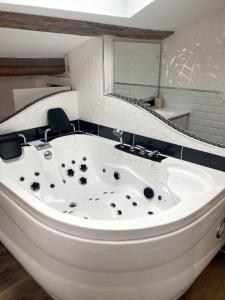 a white bath tub in a bathroom with a mirror at Escapade Romantique & Balnéo in Riom