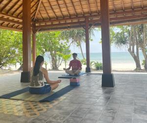 a man and woman sitting in a yoga pose on the beach at Mutiara Beach Resort in Berakit