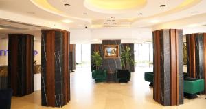 a lobby with columns and green chairs in a building at Elite World Resort Mersin Silifke in Silifke