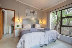 a bedroom with two beds and a large window at Chui House A Bush Retreat with Pool and AC Near Kruger Gate in Marloth Park +139 photos