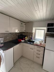 eine kleine Küche mit weißen Schränken und einem Fenster in der Unterkunft Minihouse in Kaštela