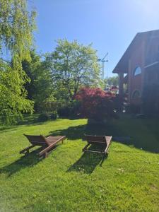 two picnic tables in the grass next to a house at B&B Rubino in Cuneo