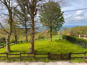 a wooden fence in a field with trees at Casa Mariuccia in Ponzone