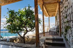 a wooden porch with a chair and a tree on it at La Tranquilla Apartment in Capri +4 photos