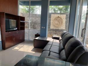 a living room with a couch and a television at Channel Stay at Machaka Villa Bandungan in Bandungan