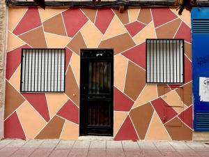 a colorful building with a door and two windows at Hostel VAM Torrejón in Torrejón de Ardoz