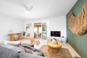 a living room with a couch and a table at Maison balinaise avec piscine chauffée, four à pizza in Saint-Louis