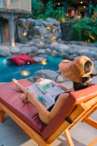 a woman laying on a bed reading a book at Butterfly Beach Resort in Taytay