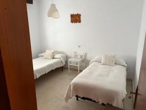 Cette chambre blanche comprend deux lits et une table. dans l'établissement Casas Manolo, à Vejer de la Frontera