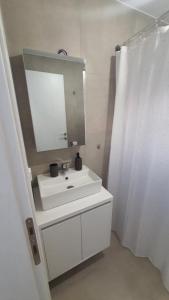 een witte badkamer met een wastafel en een spiegel bij Sunny Apartment in Ofrínion