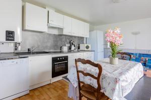 une cuisine avec une table avec un vase de fleurs dessus dans l'établissement Le Robinson - proche plage, à Marseillan