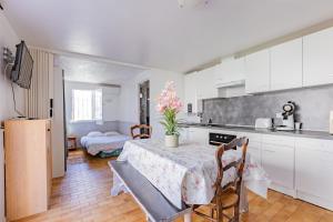 une cuisine avec des armoires blanches et une table et des chaises dans l'établissement Le Robinson - proche plage, à Marseillan