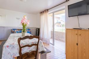 une salle à manger avec une table et une télévision dans l'établissement Le Robinson - proche plage, à Marseillan