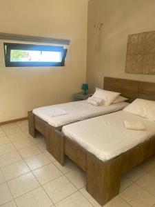two twin beds in a room with a window at Andy's Gardens in Gerani