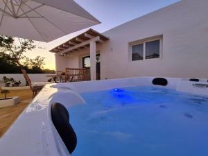a hot tub with an umbrella in front of a house at Romantica Corte dei limoni Piscinas in Piscinas