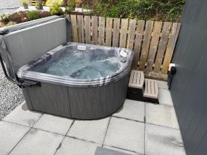 a hot tub sitting on a patio next to a fence at Tumpseys Hideaway with Hot Tub & Sunset Loch Views, Glencoe Near Fort William in Ballachulish