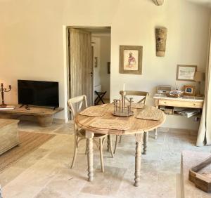 a dining room with a table and a tv at Le Mas Natán in Gordes