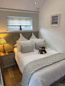 a teddy bear sitting on a bed in a bedroom at Tumpseys Hideaway with Hot Tub & Sunset Loch Views, Glencoe Near Fort William in Ballachulish