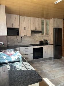 a kitchen with wooden cabinets and a black refrigerator at Springbridge Accom in Gaborone