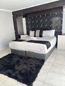 a bedroom with a large bed with a black headboard at Springbridge Accom in Gaborone