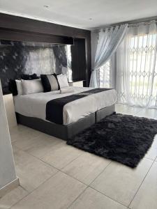 a bedroom with a large bed with a black headboard at Springbridge Accom in Gaborone
