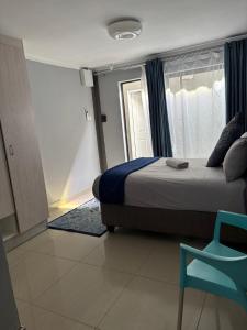 a bedroom with a bed and a window and a chair at Springbridge Accom in Gaborone