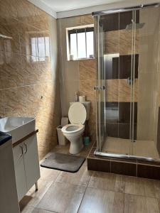 a bathroom with a toilet and a glass shower at Springbridge Accom in Gaborone