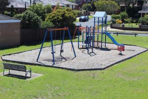 a playground in a park with a bench at Hume Villa Motor Inn in Melbourne