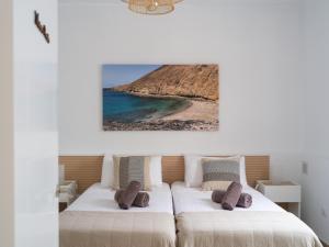 Dos camas en un dormitorio con playa y un cuadro. en La Casa de La Graciosa, en Caleta de Sebo 135 fotos más