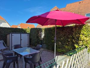 un parasol rouge sur une terrasse avec des chaises et une table dans l'établissement Maison au calme, à Camiers