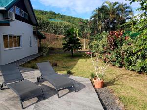 2 chaises assises sur une terrasse à côté d'une maison dans l'établissement Villa Blue Horizon Moorea, à Teavaro