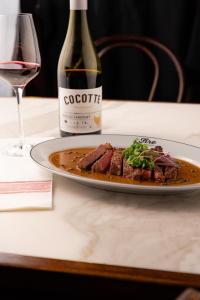 ein Teller mit Fleisch und eine Flasche Wein auf einem Tisch in der Unterkunft Boutique Hotel Catshuis in Leeuwarden