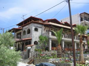 a building with palm trees in front of it at Πανσιόν Άγγελος in Ouranoupoli