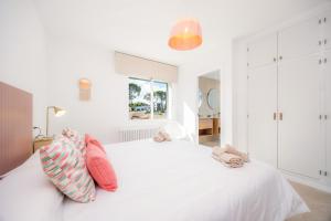 a white bedroom with a white bed with pink pillows at Villa Son Veri de la Marina in El Arenal +30 photos